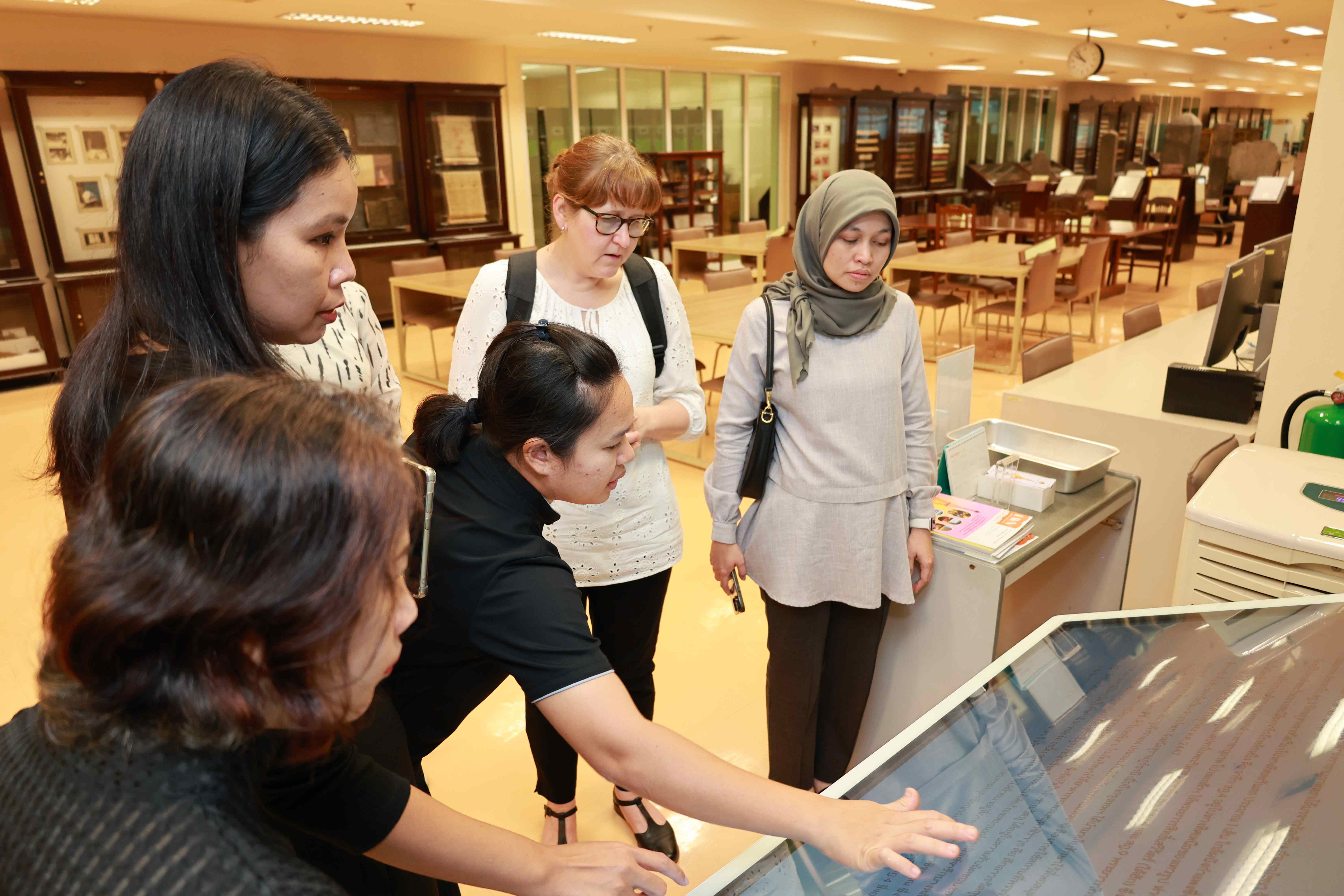 Staff of the National Library of Thailand pointing at a screen to show the digitization efforts at the National Library of Thailand